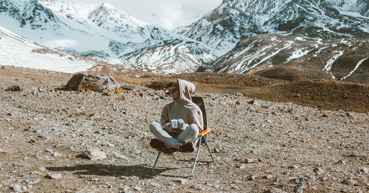 What is the stringy slimy stuff in Peace Tea? - Full body of man sitting on folding chair and drinking tea with high mountains covered with snow on background