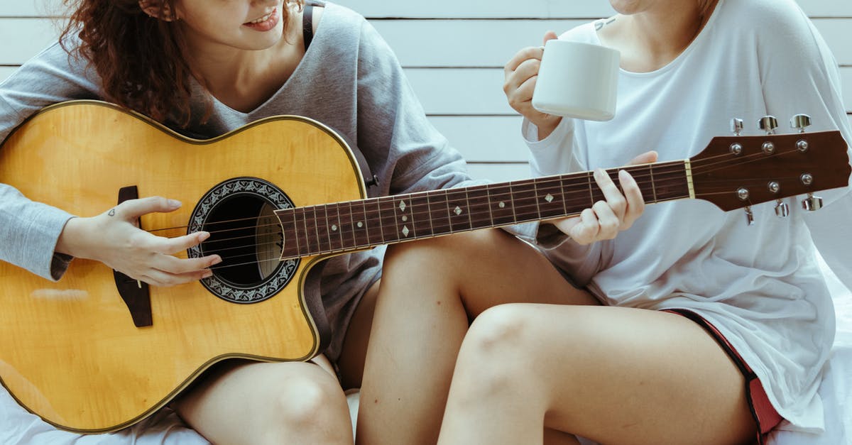 What is the stringy slimy stuff in Peace Tea? - Crop female friends in tee shirts playing on guitar and chatting while sitting on white terrace with tea