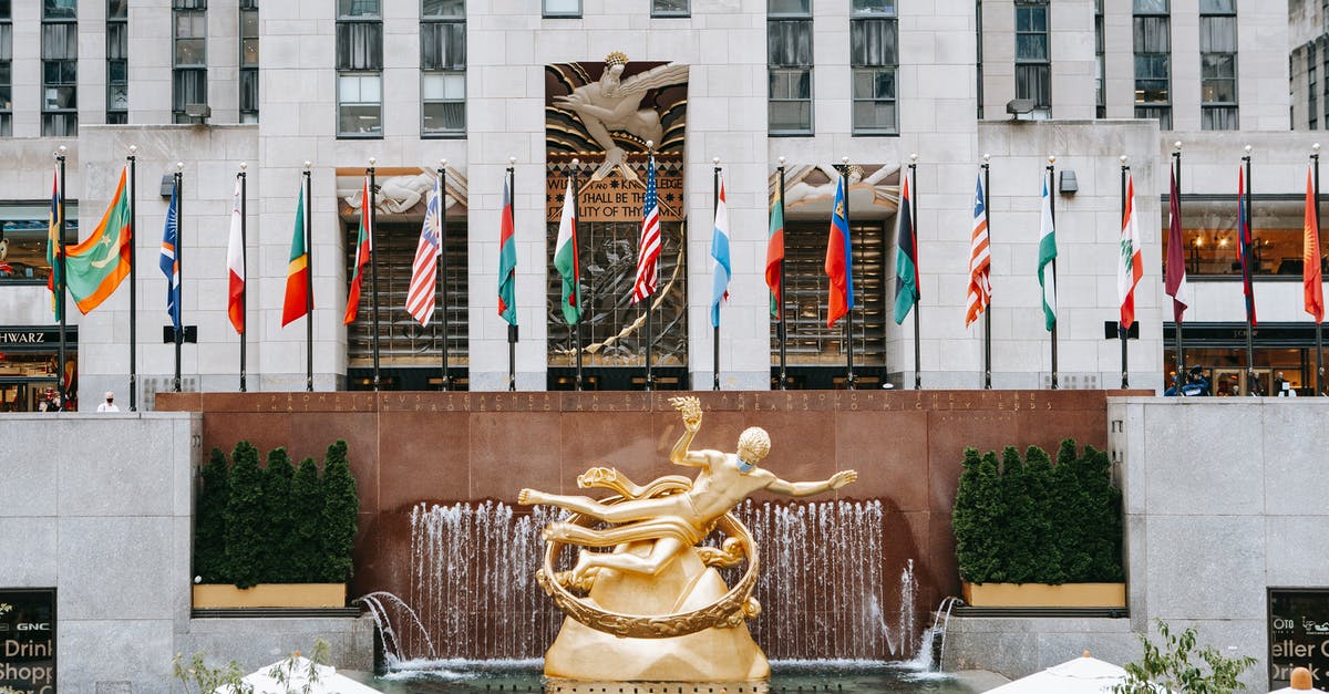 What is the US equivalent of Golden Syrup (UK)? - Golden Prometheus statue located near entrance of Rockefeller center with flags on street in New York city in modern district