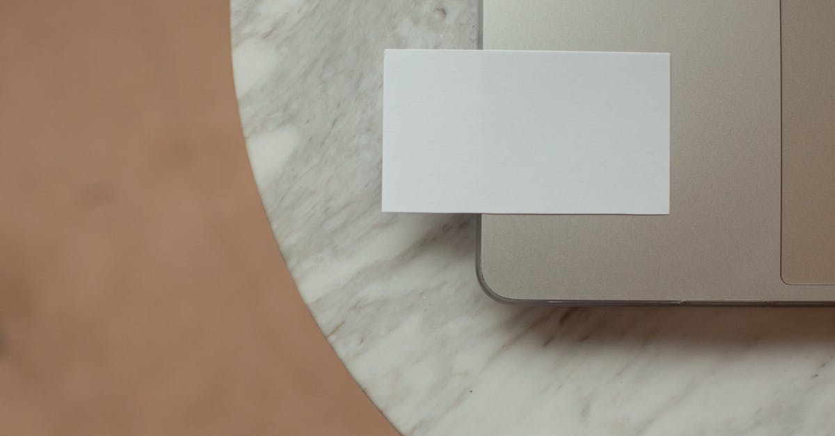 What is this oddly shaped hinged device with indentations? - Top view white mock up business card with copy space placed on modern opened netbook on round marble table in light room