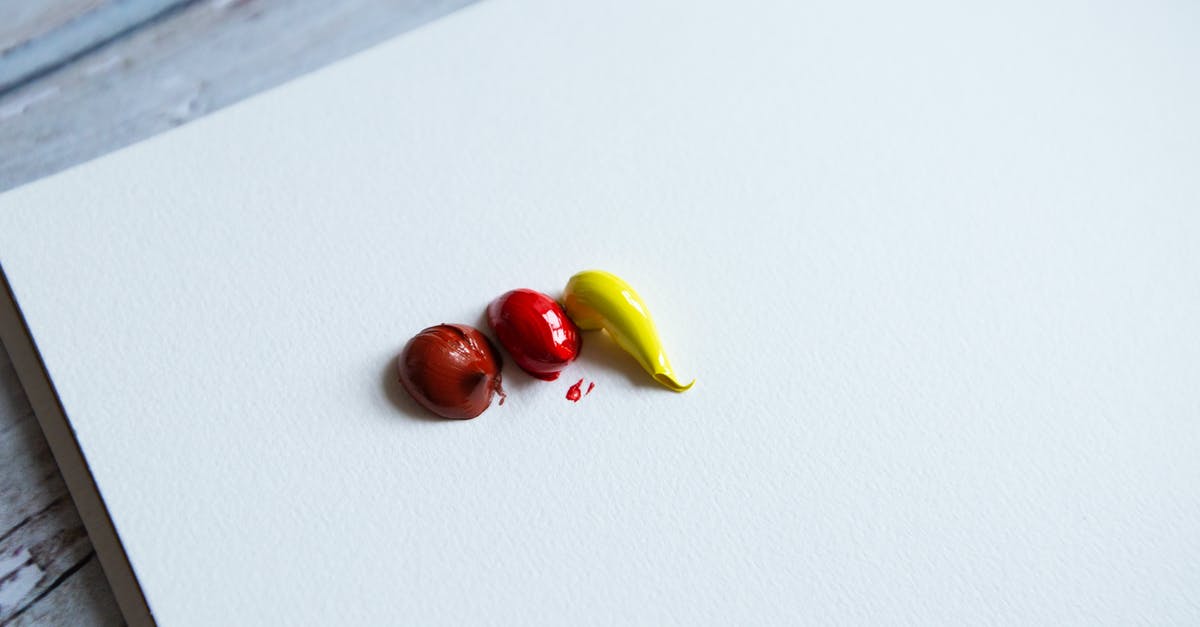 What is this yellow and white mass inside my red cabbage? - From above of red and yellow paint blobs on clear white canvas placed on wooden surface in light art studio