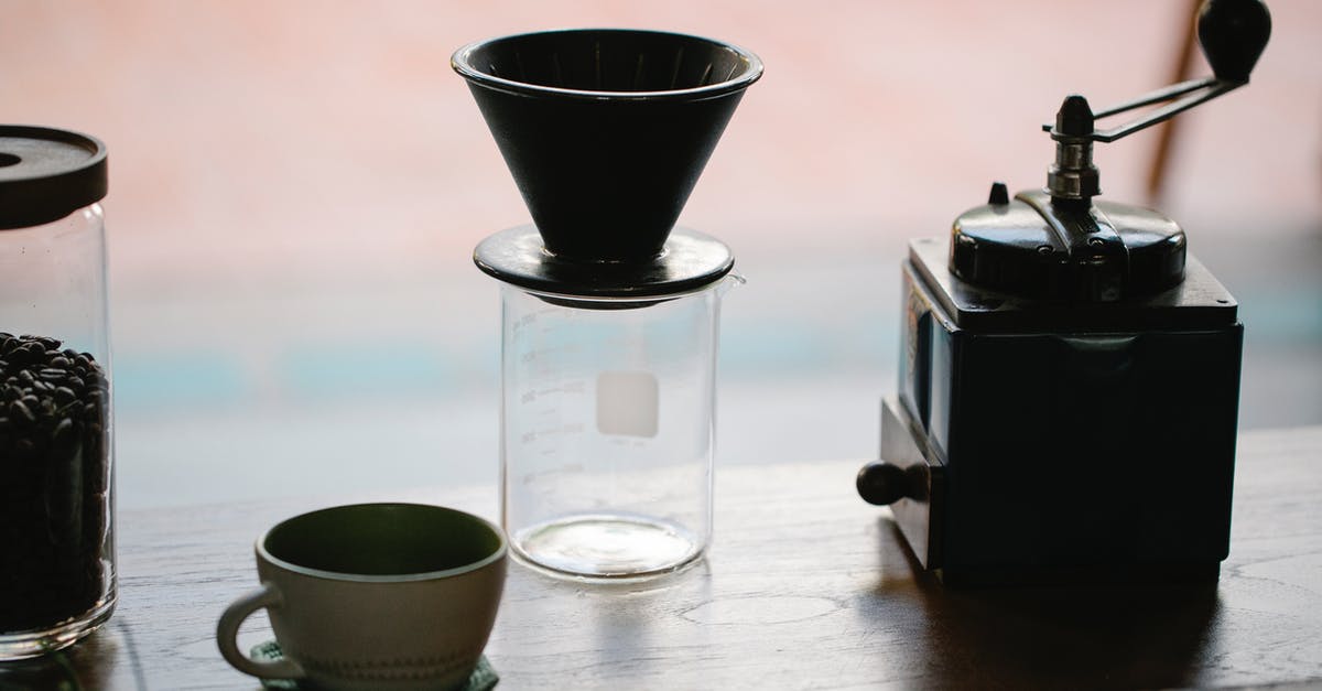What kind of coffee grinder is best? - From above of manual coffee grinder with pour over coffeemaker placed in wooden table with ceramic cup and glass jug with roasted beans in morning