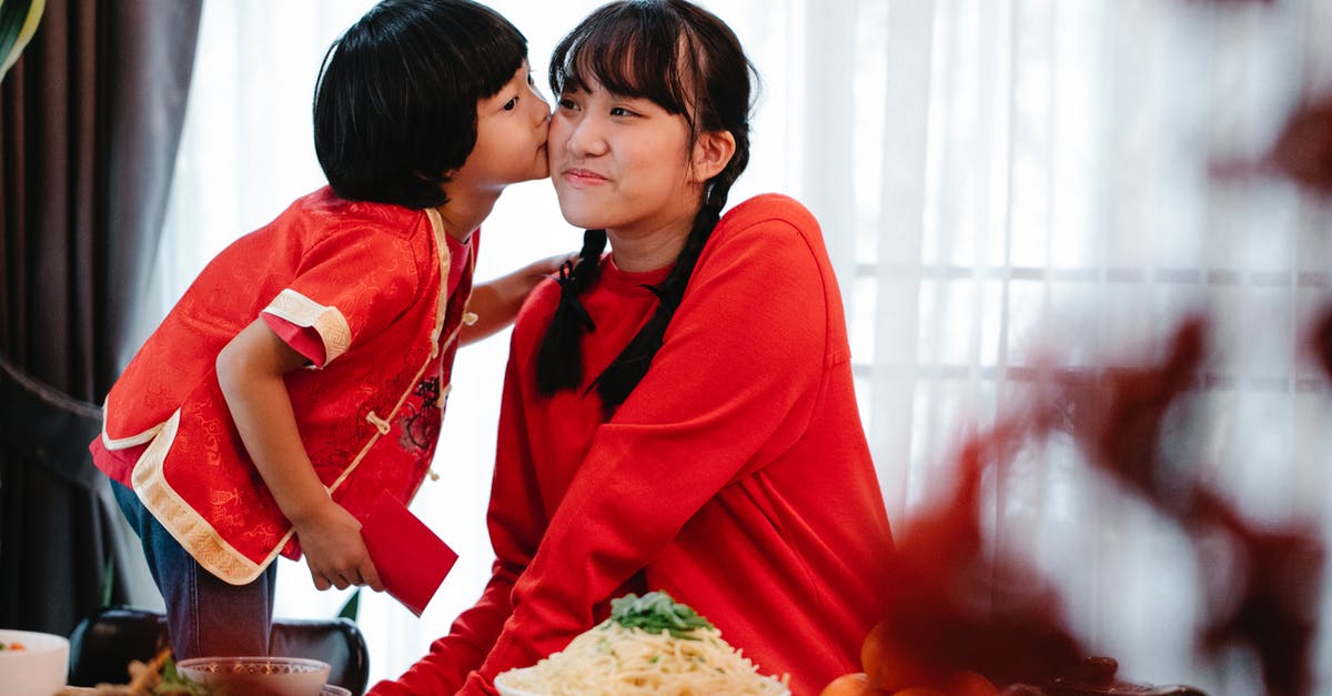 What kind of foods react with aluminium pressure cookers? - Asian boy kissing sister during New Year holiday at home