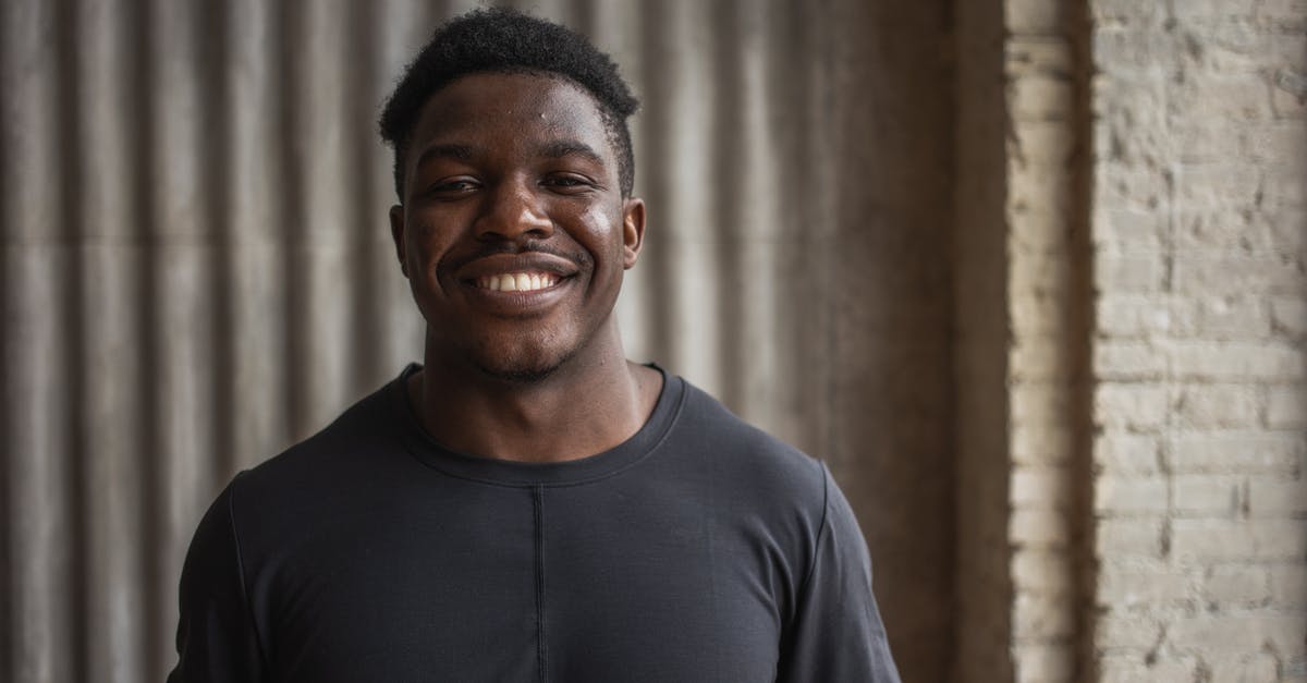 What kind of frosting doesn't need to be refrigerated? - Content adult black male athlete looking at camera with toothy smile against ribbed wall