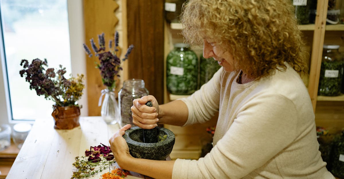 What kind of mortar and pestle will be strong enough for grinding date pits? - A Woman Grinding Petals with Mortar and Pestle