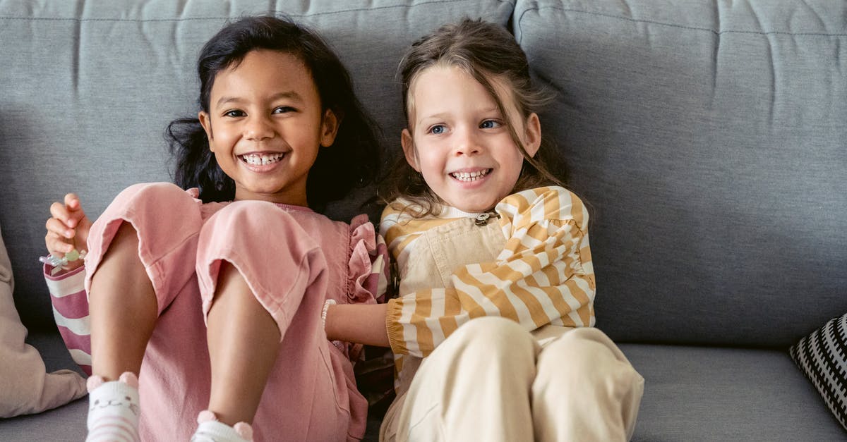 What kind of wok do I have? - Cheerful best multiracial friends in striped clothes interacting on couch in living room in house