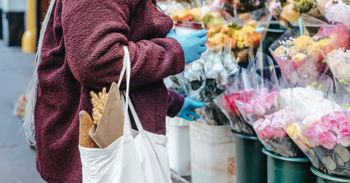 What kinds of grocery stores tend to carry guava? - Woman with paper cup of coffee buying flowers on street