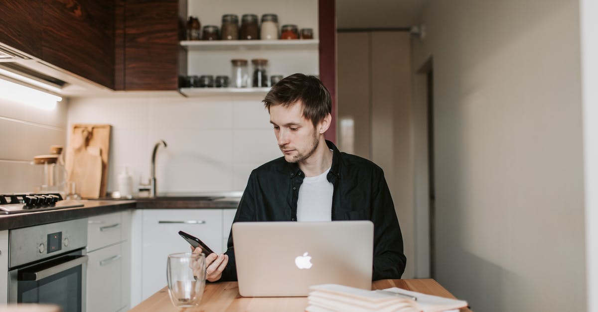 What knives are "required" for a serious home kitchen? - Young male remote employee in casual wear chatting on cellphone while sitting at wooden table in front of open netbook and copybook with glass of water in flat