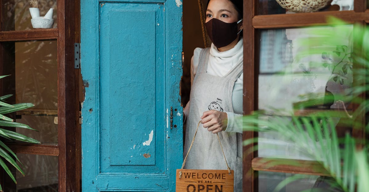 What makes a bread either close or open crumbed/textured? - Calm young Asian female wearing casual clothes and face mask standing at shabby rural shop doorway and removing open sing