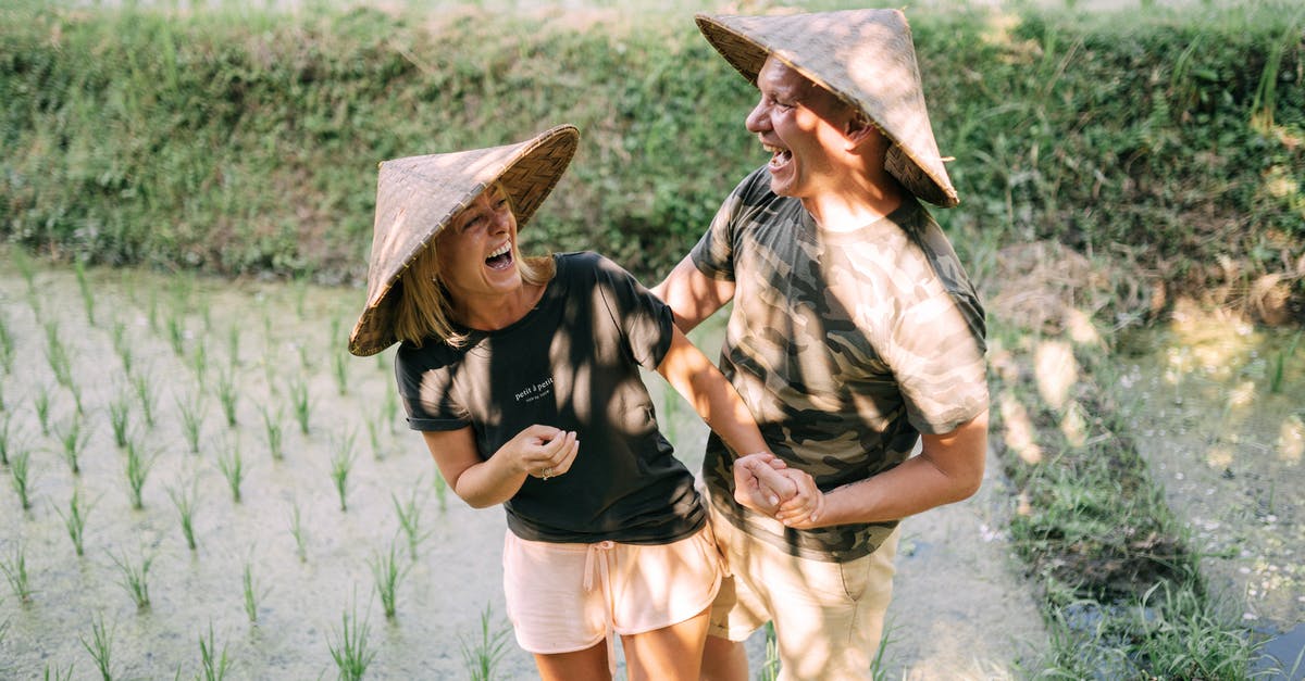 What makes rice wet? - Smiling Couple Standing on Rice Field