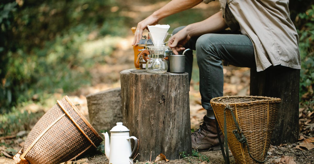 What material is best for a pour over coffee brewer? - Side view of crop anonymous male harvester with manual coffee grinder and pour over maker preparing hot beverage on pathway