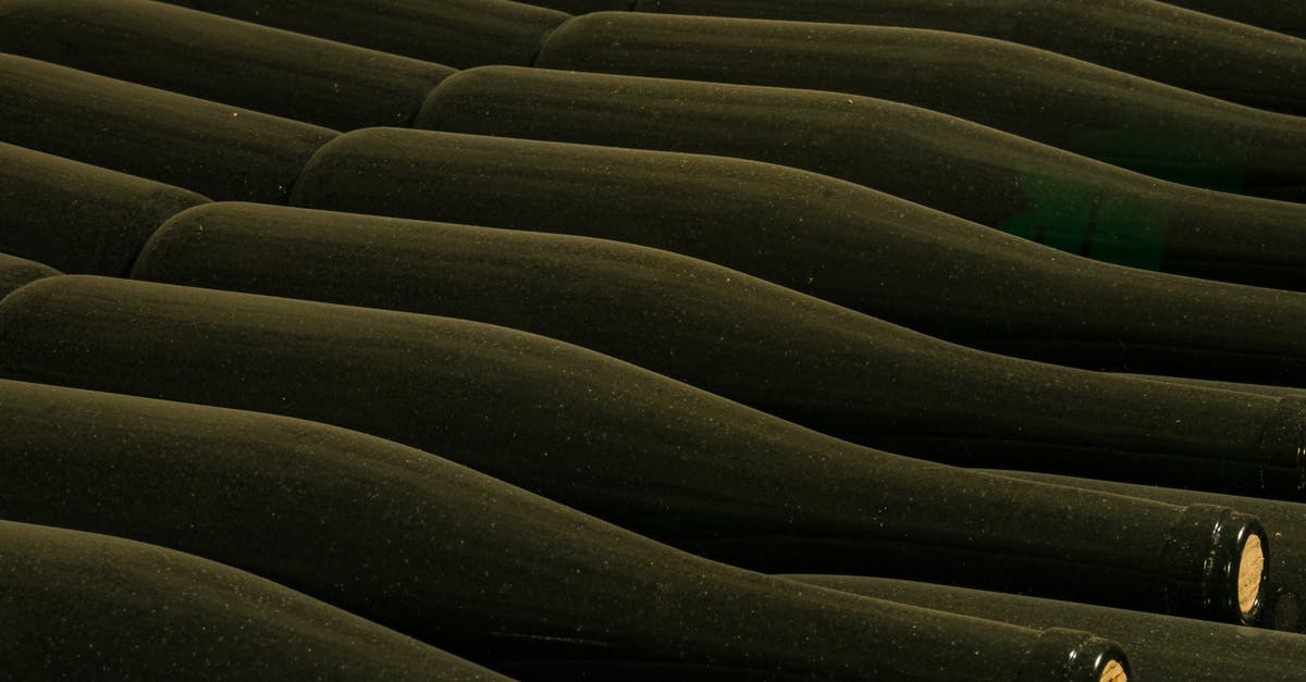What non-alcoholic liquid can I use to store Ginger, both cooked and raw? - From above of glass bottles placed side by side in rows in winery cellar