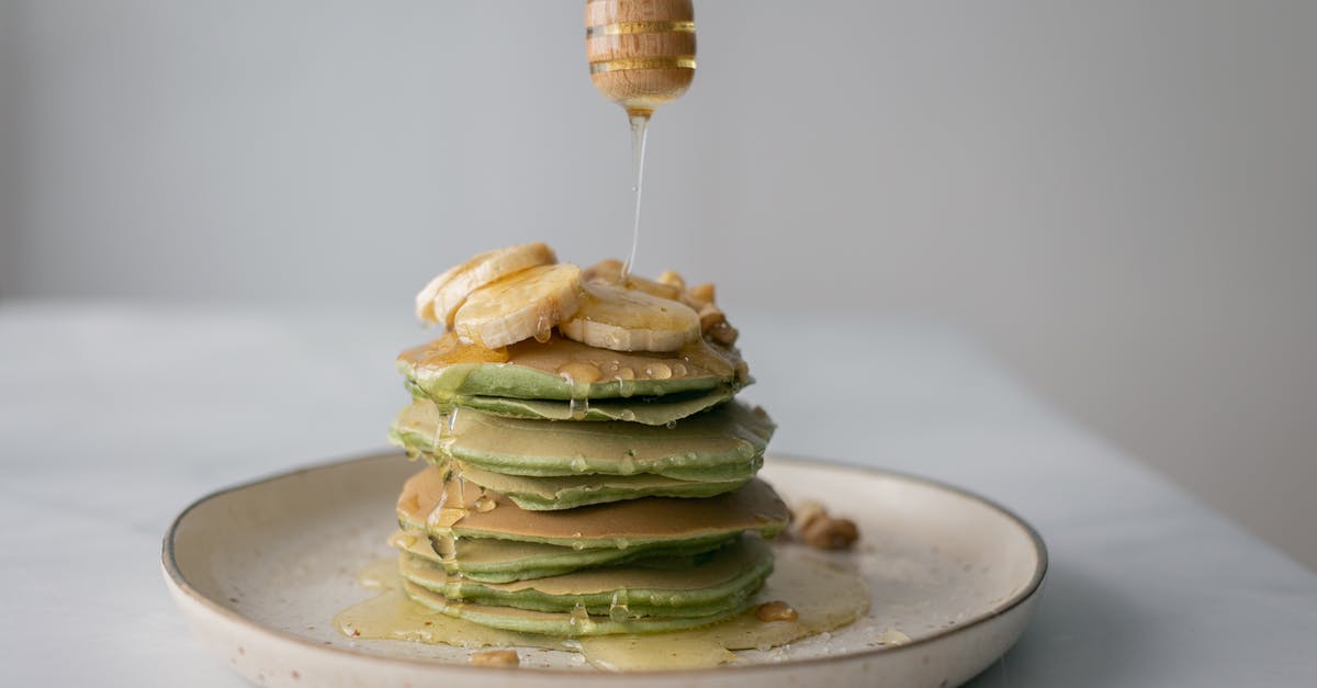 What nutritional differences are there between honey and table sugar (sucrose)? [closed] - Tasty pancakes with fresh bananas served on plate and table on white blurred background