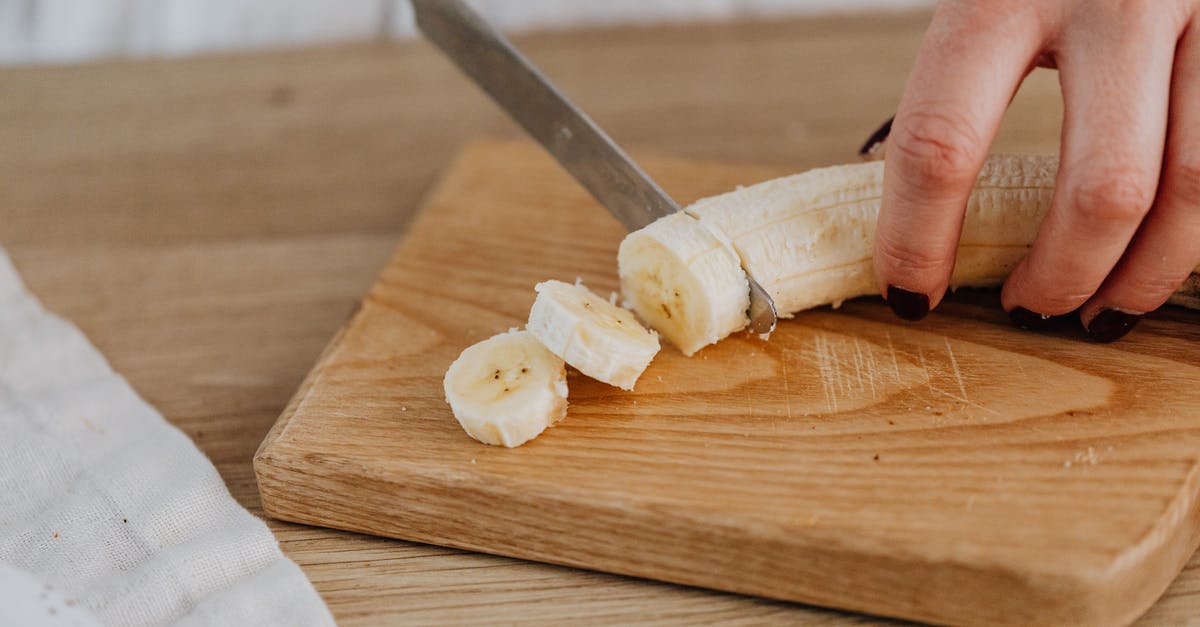 What preparation is done to banana peppers? - A Close-up Photo of a Person Slicing a Banana 