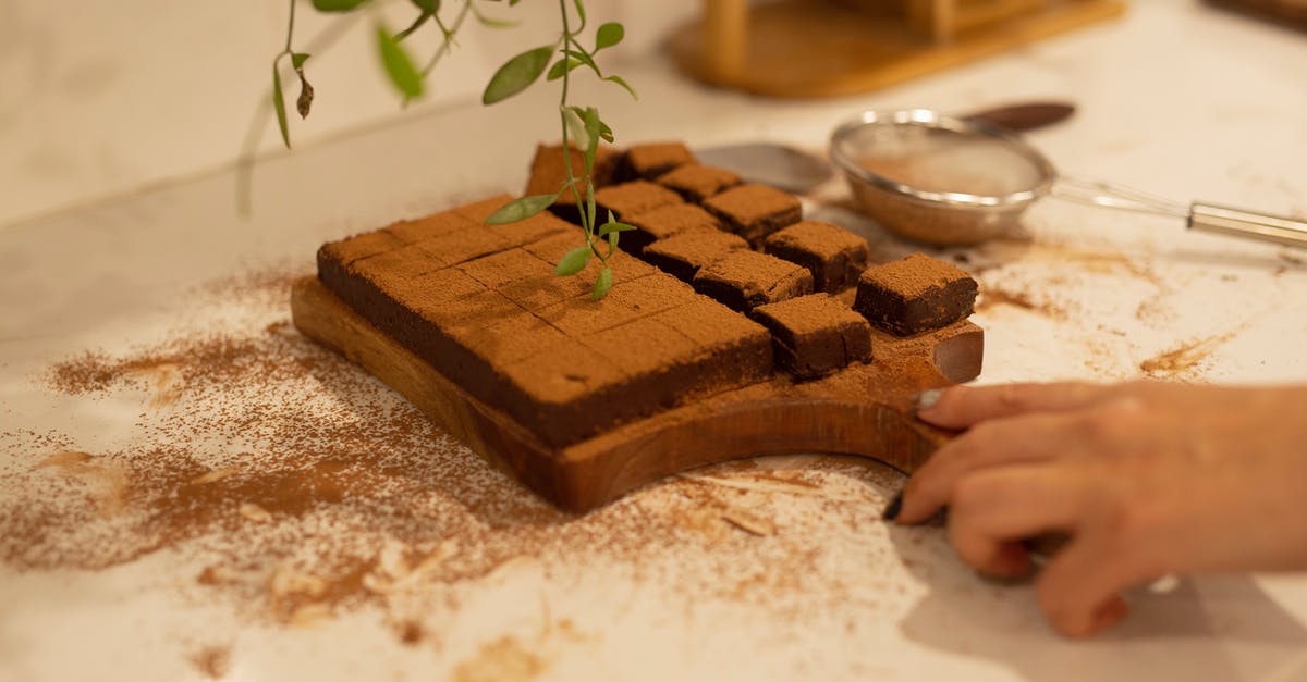 What should be added to brownies when reducing cocoa powder and vanilla extract? - Woman Holding Wooden Board with Homemade Chocolate Brownie