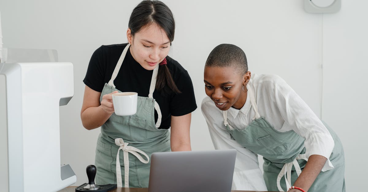 What special knowledge or skills about coffee do baristas have? - Young Asian coffee house worker explaining to new African American coworker how to use special computer program during break at work