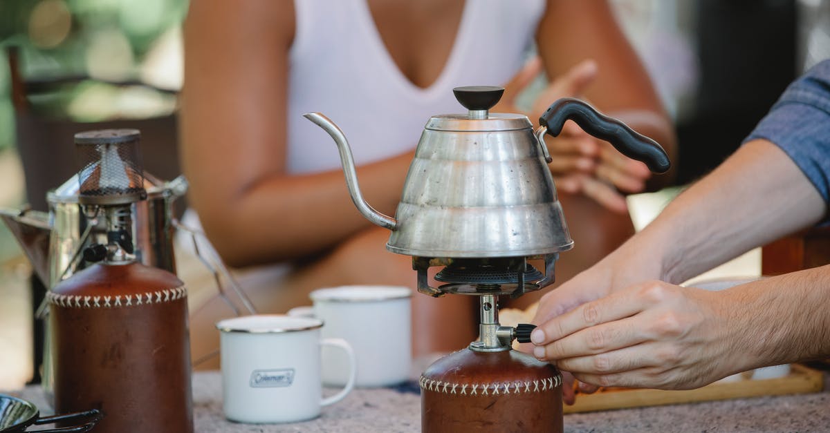 What temperature is a rolling boil? - Crop couple heating metal kettle on camp stove