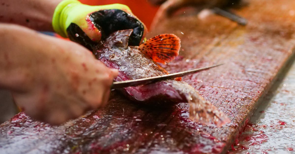 what to do with fish steaks that still have scales on? - A Person Removing the Scales of a Fish