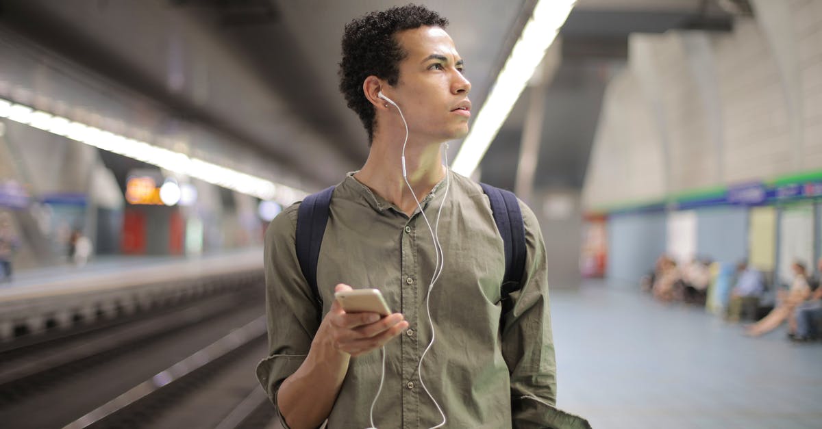 What to expect from canned bear meat? - Young ethnic man in earbuds listening to music while waiting for transport at contemporary subway station