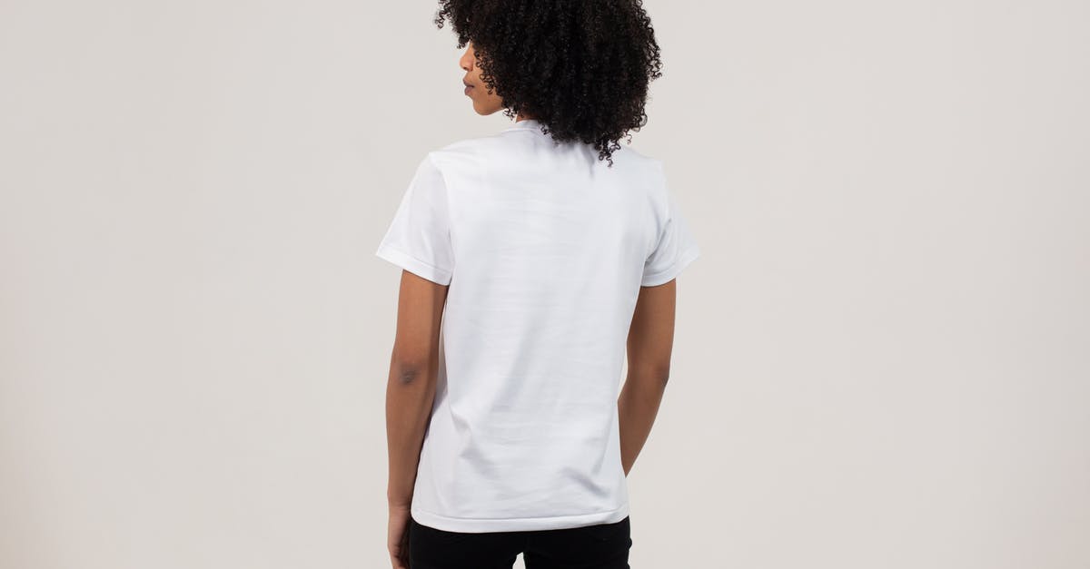 What to look for in a Stand Mixer? - Back view unemotional young African American female wearing casual white t shirt and black pants while standing against light wall