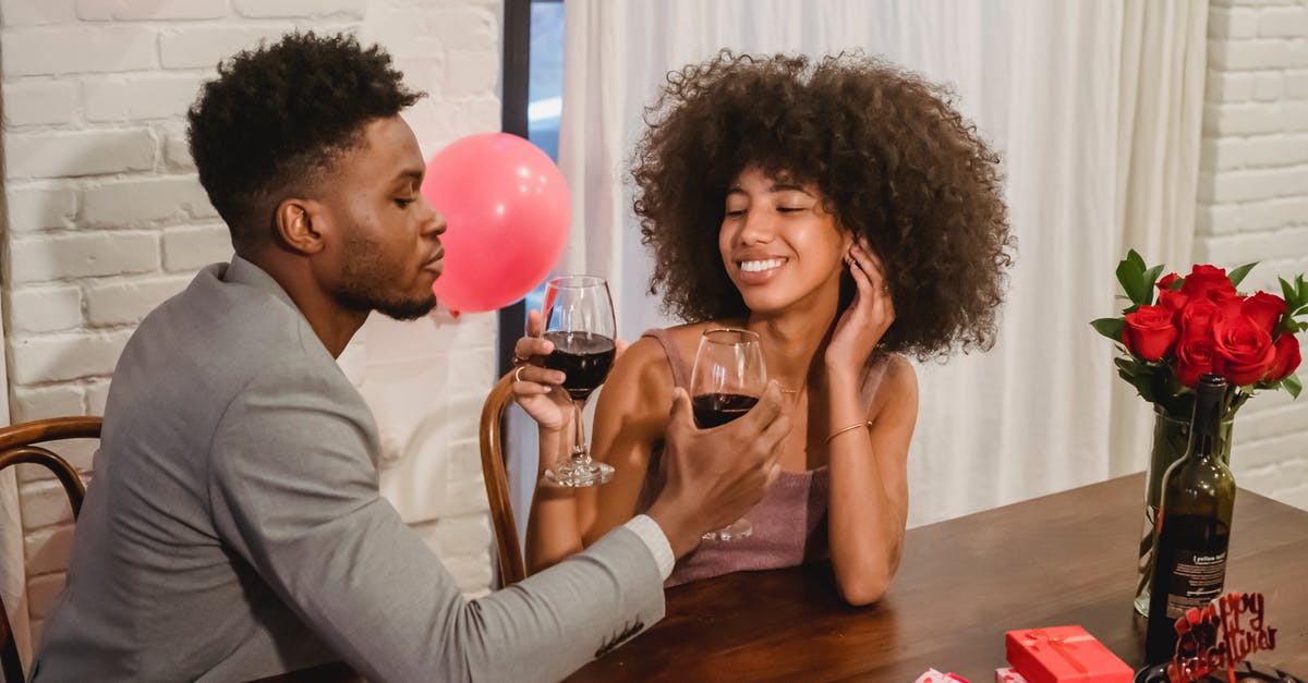 What wine(s) would you substitute for sweet red vermouth? - Happy young Black couple toasting with red wine while sitting at table with wineglasses and celebrating Saint Valentine Day