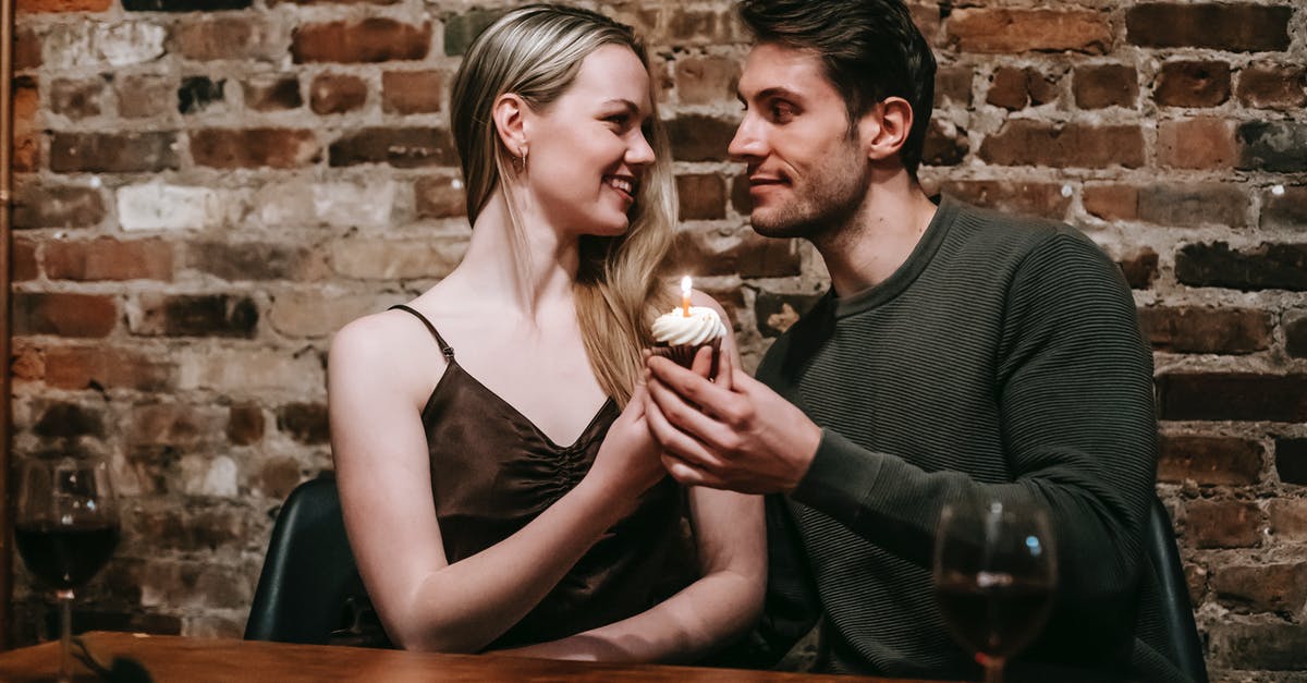 What wine(s) would you substitute for sweet red vermouth? - Happy young couple in elegant clothes sitting at table and celebrating birthday with small cupcake and candle near glasses with red wine and brick wall while looking at each other