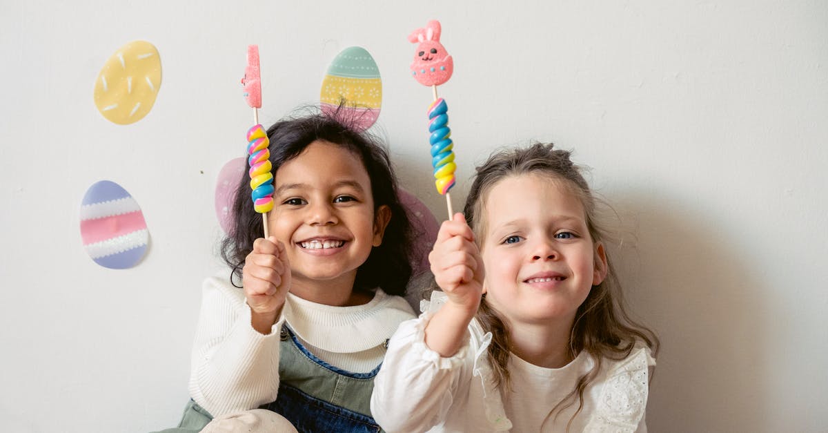 What’s the minimum sugar to egg white ratio in Swiss buttercream? - Cheerful multiracial children with sweet Easter bunny candies looking at camera while sitting on white background with egg decorations during holiday celebration