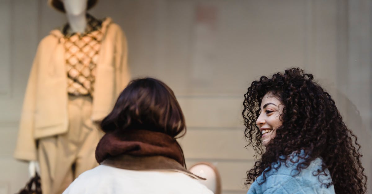 When's the best time to buy a Thanksgiving turkey? - Content young ethnic women smiling at street while looking at trendy clothes on mannequin