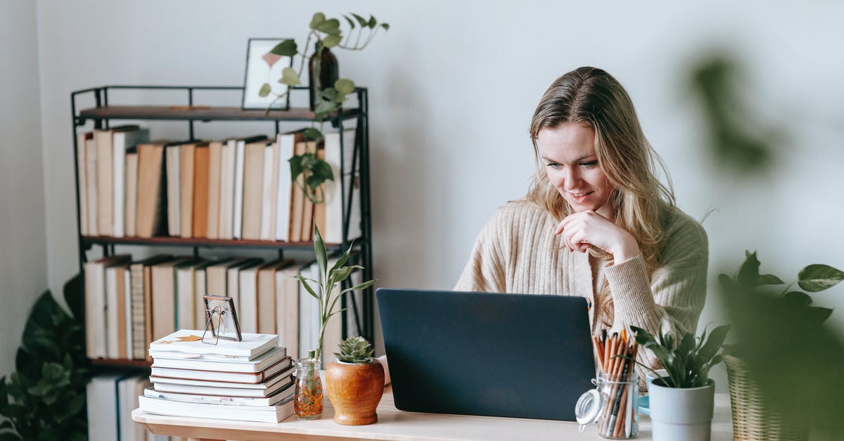 When are pot lids useful? - Interested young female remote employee surfing internet on netbook at table with potted plants against bookshelves in house on light background