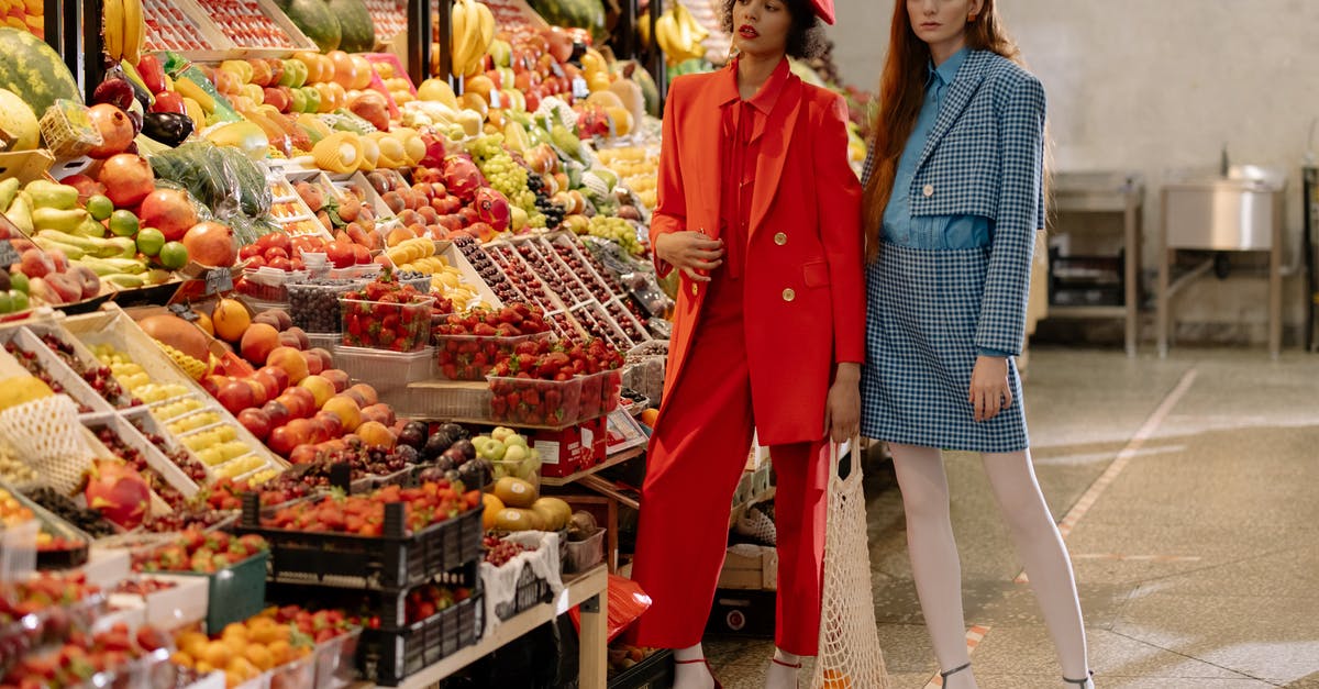 When comparing food processor models, why do some have additional blades? - Woman in Orange Long Sleeve Shirt Standing Beside Woman in Blue Long Sleeve Shirt