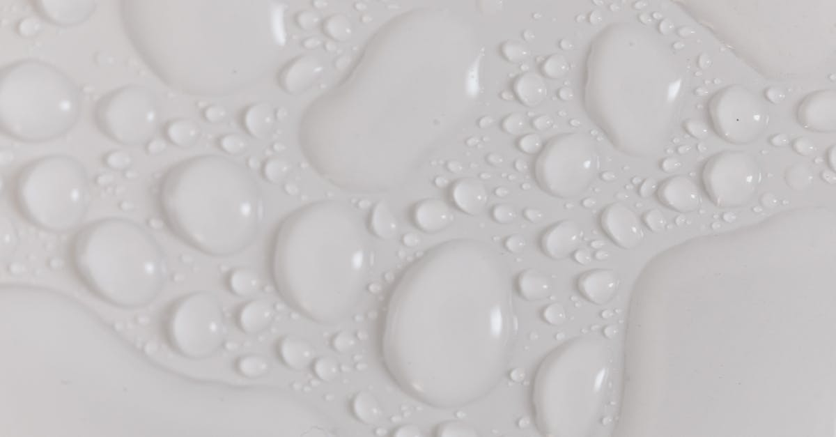 When heating up a pizza, edges burn while middle still liquid - Closeup top view of wet plain white background of droplet with translucent clean still water drops of different shapes and sizes