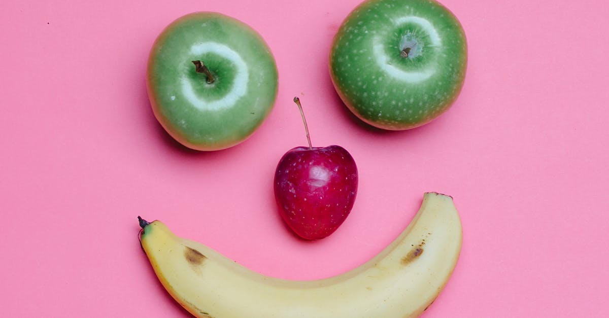 When I make apple juice, what's in the foam on top? - Top view of fresh ripe banana and green and red apples arranged as smile on pink background