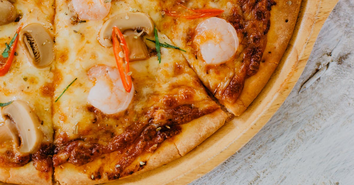 When is it appropriate to serve shrimp with the tail still attached? - Appetizing baked sliced seafood pizza with mushrooms