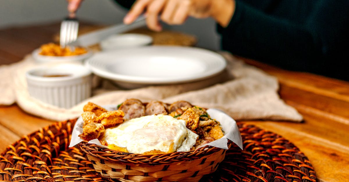 When making fried rice, how does the amount of heat affect the taste of the food? - Crop faceless person enjoying tasty lunch while sitting at table with bowl of delicious fried egg and crispy sausages When making fried rice, how does the amount of heat affect the taste of the food? - Crop faceless person enjoying tasty lunch while sitting at table with bowl of delicious fried egg and crispy sausages