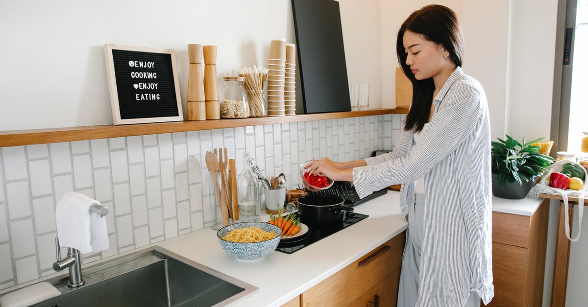 When to add vegetables in slow cooker? - Asian woman cooking near stove