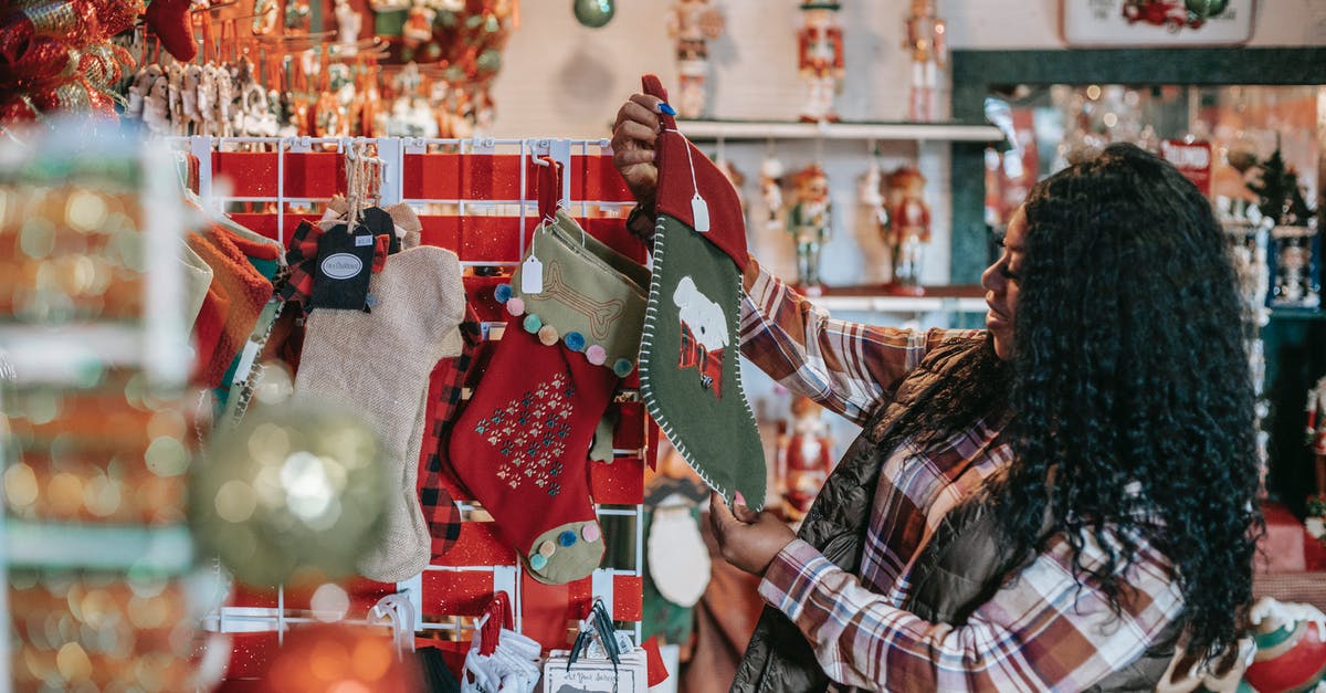 Where can I buy American style bread flour in Europe - Side view of smiling African American female with Xmas sock in shop with decorative baubles and gifts