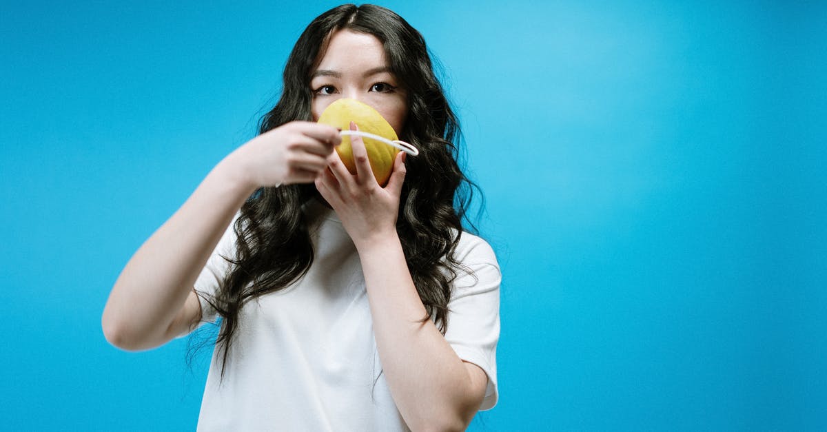 Where do I find the fruit tamarind? - Woman in White Shirt Holding Yellow Fruit