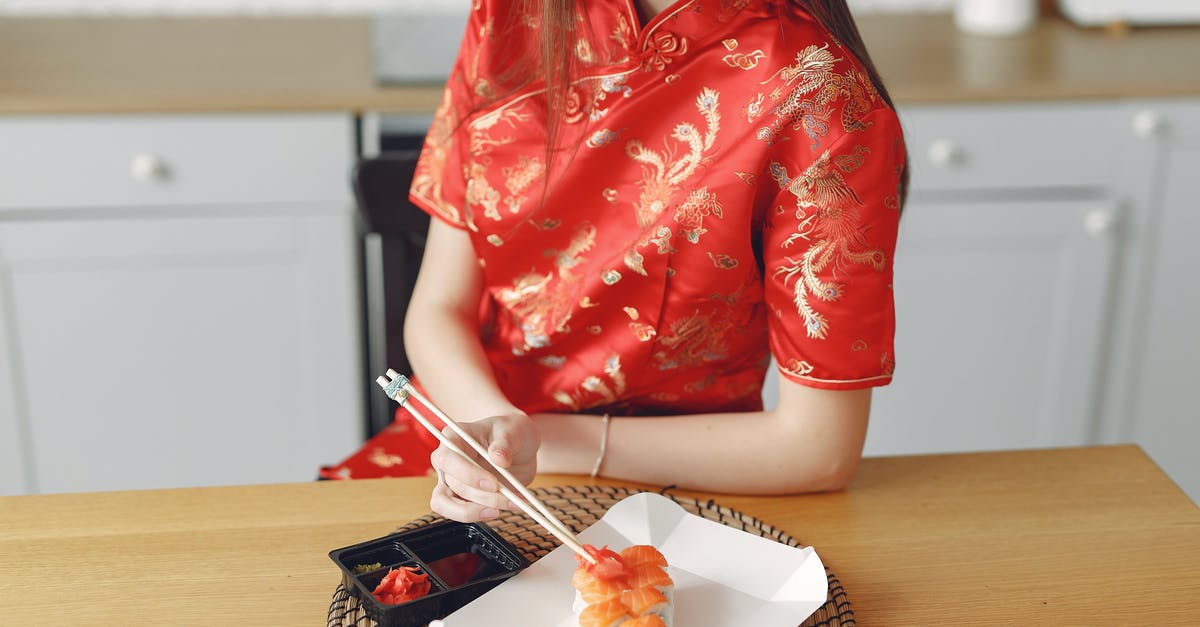 Where does the Asian dish "sang choi bow" come from? - Crop female eating sushi in modern kitchen