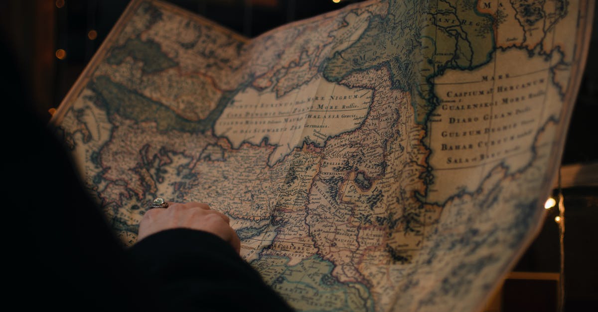 Where to find a large individual brownie pan? - From behind anonymous person examining antique world map printed on large paper in blue colors in dark room