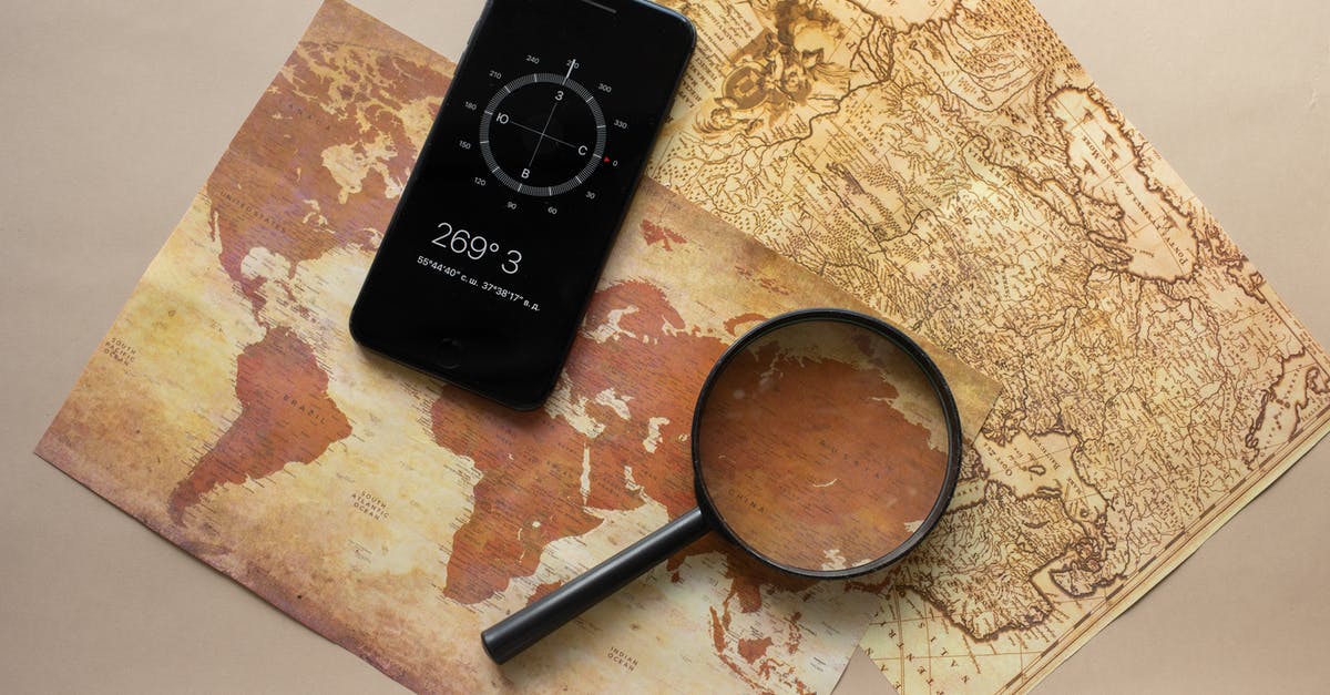 Whetstone with an angle guide - Top view of magnifying glass and cellphone with compass with coordinates placed on paper maps on beige background in light room