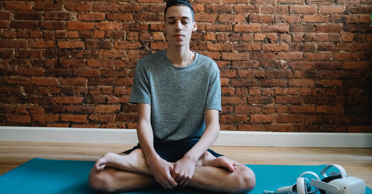 Which cooking device allows flexible temperature programming? - Full body of focused male teenager in activewear meditating in lotus pose on mat near VR glasses