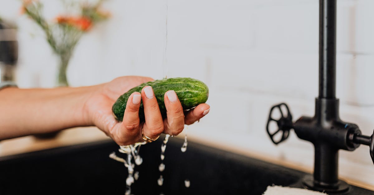 Which end of the cucumber should I save for later? - Woman Washing Cucumber under Tap Water 