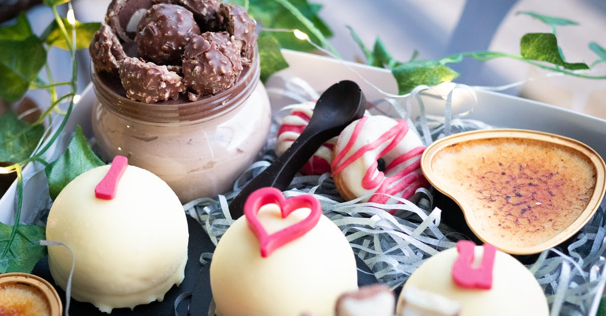 White chocolate ganache won't set - Tasty sweet little cakes covered with white chocolate and decorated with pink inscription placed in box near glass jar of chocolate sweets and doughnuts