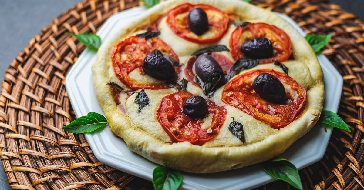 White dots on pizza or focaccia after baking - From above of tasty pizza with tomato and olive on plate with basil leaves