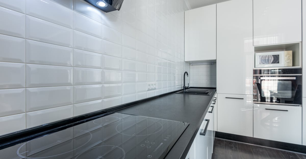 White residue after putting bacon grease laden cookware in dishwasher - Interior of modern light white kitchen furnished with white cupboards and appliances with wooden floor and tiled wall