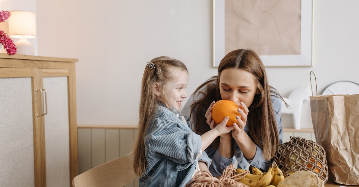 Who knows what this fruit is called? - Woman in Blue Denim Jacket Holding Orange Fruit