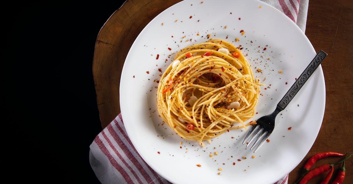 whole vs ground spices - Top view of tasty noodles with garlic and chili pepper slices decorated with ground pepper mix on table in cafe