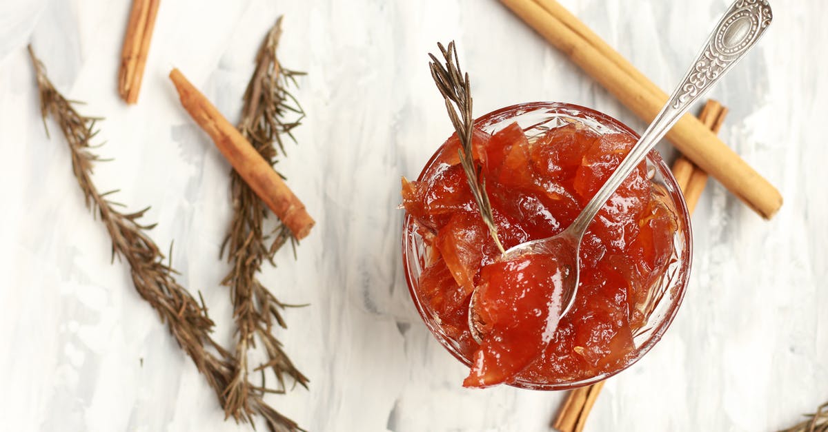 why a citric fruit rind is cooked several times to make a marmalade - Glass bowl of jam with rosemary sprigs and cinnamon sticks