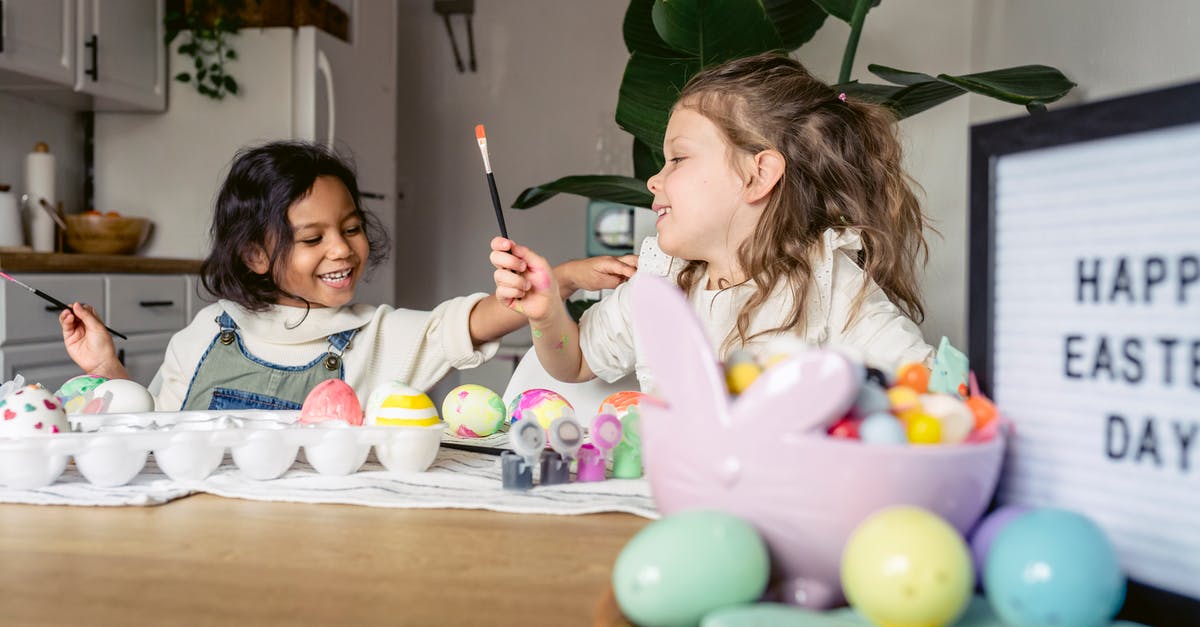 Why are croissants brushed twice with egg glaze? - Smiling little multiracial kids in casual clothes sitting at wooden table and coloring Easter eggs with brushes and forms in light apartment