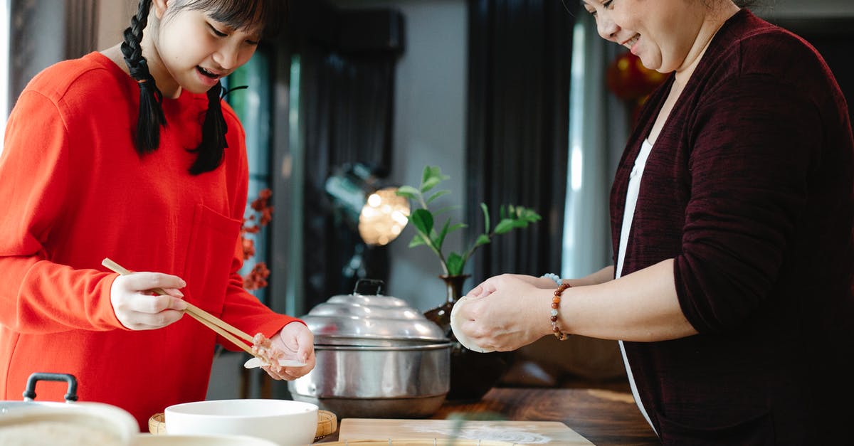 Why are my doughnuts raw in the middle? - Crop Asian grandma with teen preparing dim sum in kitchen